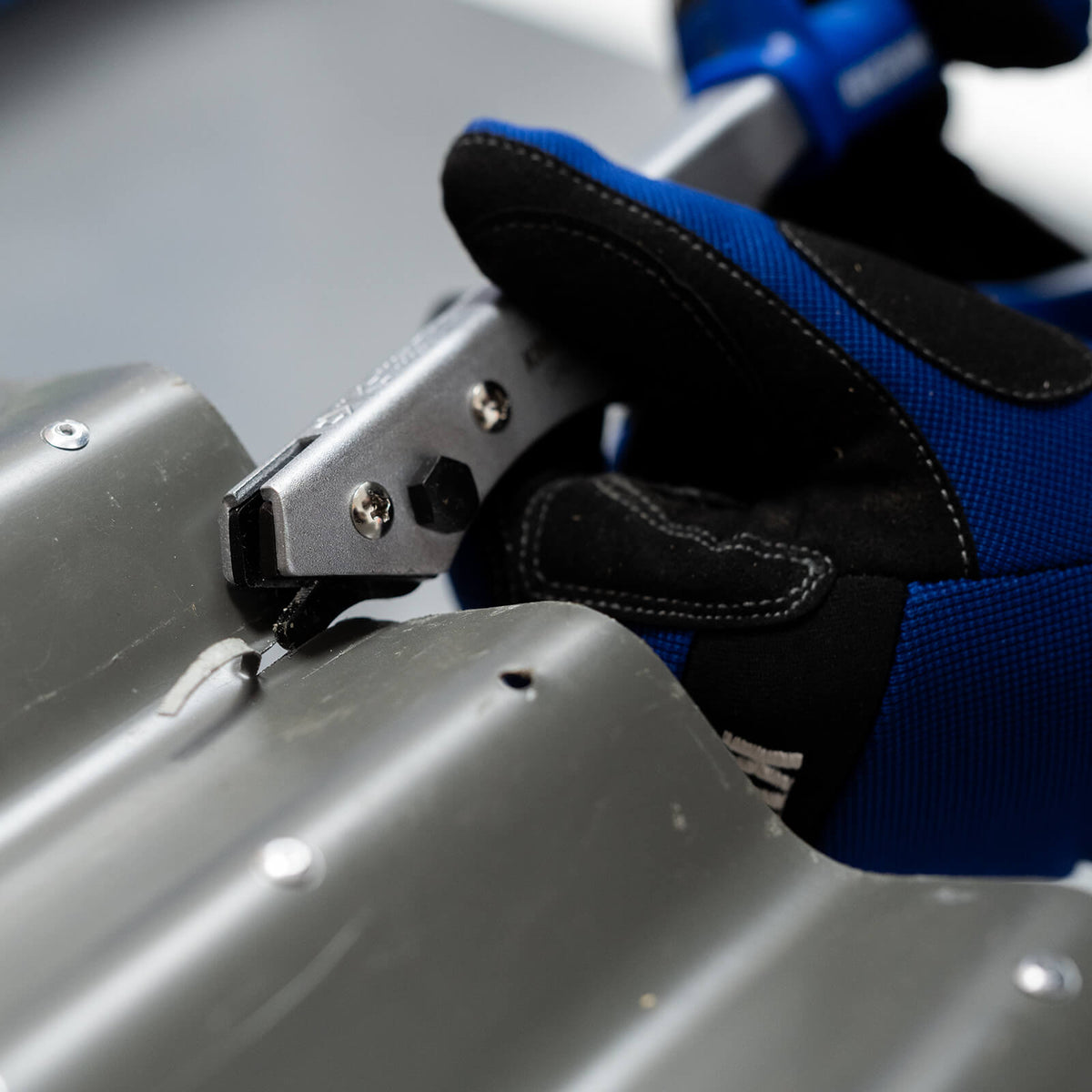 This is an image of a gloved hand using a metal tool on a metal surface, showcasing welding supplies at Kennedys Welding Supplies in Derwent Park TAS