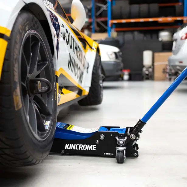 This is an image of a Kincrome 1.45 ton racing car jack lifting a race car tire in a workshop, available at Kennedys Welding Supplies in Derwent Park, TAS, offering tool shop, welding specialists, laser cutting, power tool repairs, and onsite tool truck services.