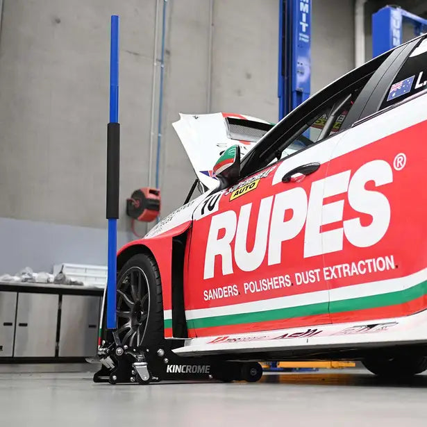 This is an image of a Kincrome 1-ton aluminum racing jack lifting a red Rupes racing car in a workshop, featured by Kennedys Welding Supplies in Derwent Park, TAS.