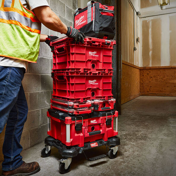 This is an image of a person handling red Milwaukee Packout toolboxes stacked on a wheeled base in an industrial setting at Kennedys Welding Supplies in Derwent Park, Tasmania, offering tool shop and welding specialist services.