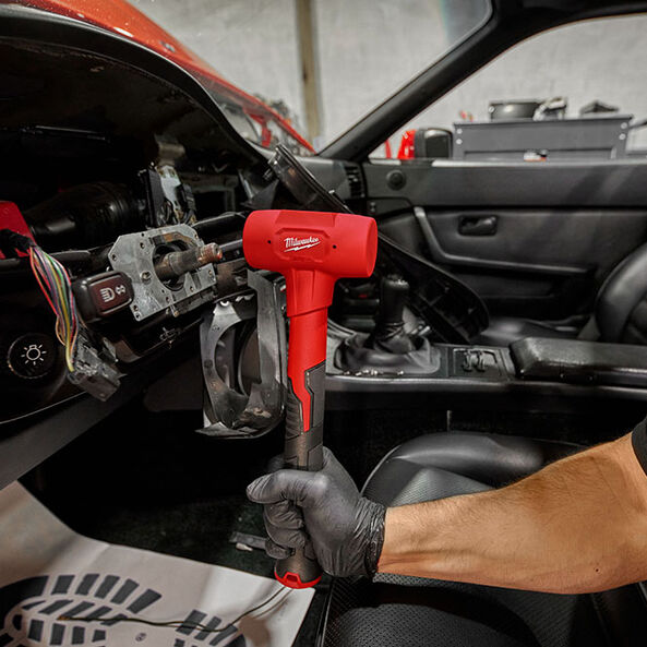 This is an image of a hand holding a Milwaukee power tool inside a car dashboard, showcasing Kennedys Welding Supplies in Derwent Park TAS offering tool shop and power tool repairs