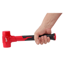 This is an image of a hand holding a red and black Milwaukee rubber mallet, showcasing welding and tool supplies from Kennedys Welding Supplies in Derwent Park, TAS, offering tool shop and power tool repairs.