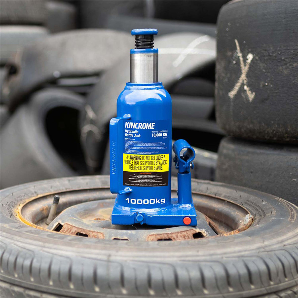This is an image of a blue Kincrome 10000kg hydraulic bottle jack on a car tire, offered by Kennedys Welding Supplies in Derwent Park TAS, welding specialists and tool shop.