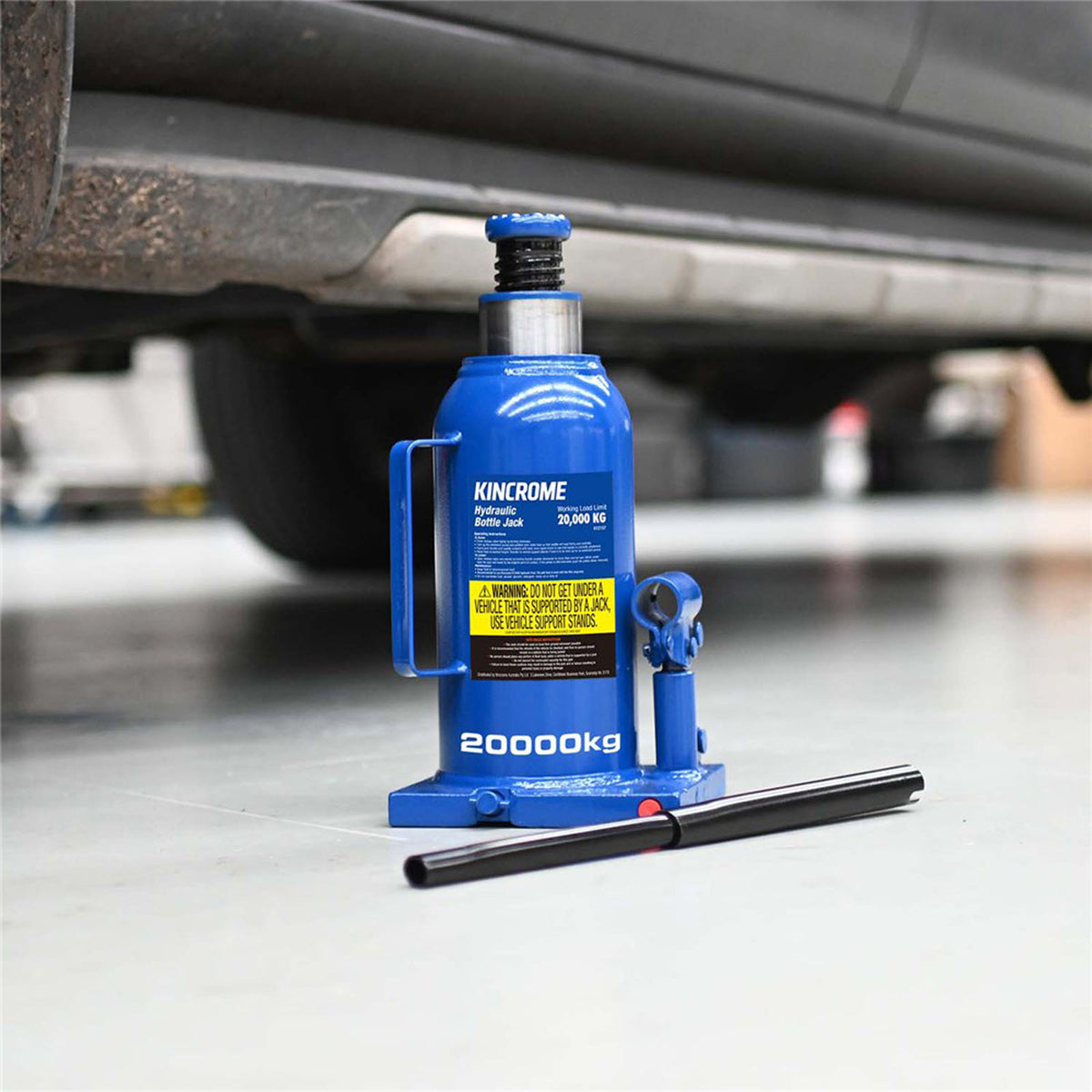 This is an image of a blue Kincrome hydraulic bottle jack 20000kg under a vehicle at Kennedys Welding Supplies Tool Shop in Derwent Park TAS