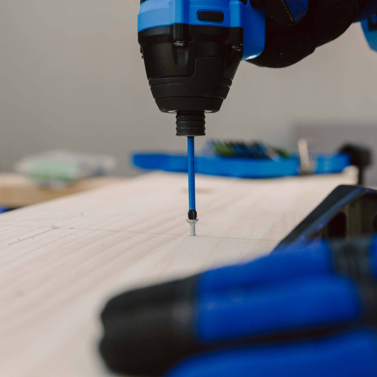 This is an image of a close-up blue cordless drill driving a screw into wood, showcasing power tools at Kennedys Welding Supplies in Derwent Park TAS, offering tool shop and welding specialists services.