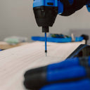 This is an image of a close-up blue cordless drill driving a screw into wood, showcasing power tools at Kennedys Welding Supplies in Derwent Park TAS, offering tool shop and welding specialists services.