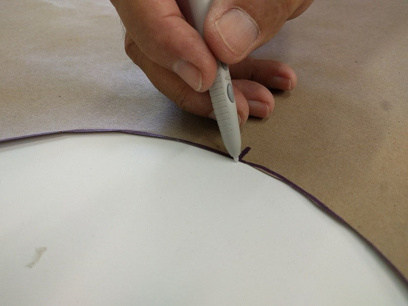 This is an image of a hand using a marker to trace a pattern on brown material, representing precision work by Kennedys Welding Supplies in Derwent Park TAS offering tool shop and welding specialist services