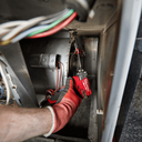 This is an image of a gloved hand using a Milwaukee power tool inside machinery, by Kennedys Welding Supplies in Derwent Park TAS