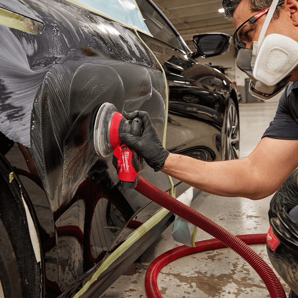 This is an image of a worker polishing a black car with a Milwaukee sander, showcasing Kennedys Welding Supplies in Derwent Park, TAS, offering tool shop, welding services, and power tool repairs