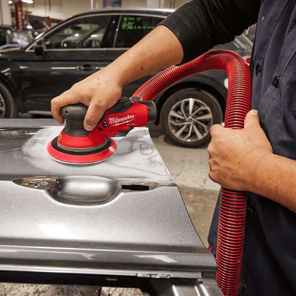 This is an image of a person using a red Milwaukee sander on a car door panel in a workshop, showcasing welding and tool repair services by Kennedys Welding Supplies in Derwent Park, TAS
