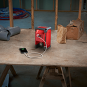 This is an image of a red laser level charging a smartphone on a construction site table, representing Kennedys Welding Supplies in Derwent Park TAS, offering tool shop and laser cutting services