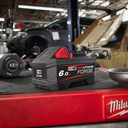 This is an image of a Milwaukee M18 RedLithium Forge 6.0Ah battery on a red tool bench in a workshop, representing Kennedys Welding Supplies in Derwent Park TAS offering tool shop, power tool repairs, and welding specialists.