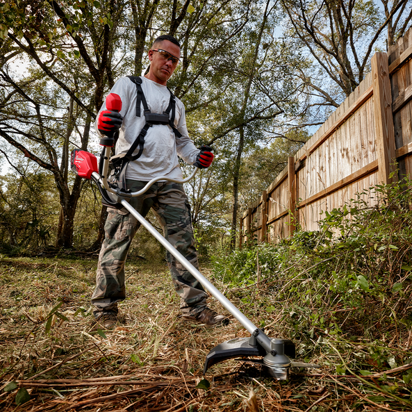 This is an image of a man using a red brush cutter for outdoor landscaping, showcasing Kennedys Welding Supplies in Derwent Park TAS, offering tool shop and power tool repairs