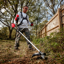 This is an image of a man using a red brush cutter for outdoor landscaping, showcasing Kennedys Welding Supplies in Derwent Park TAS, offering tool shop and power tool repairs
