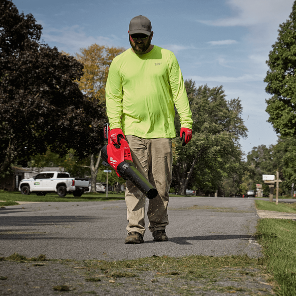 This is an image of a man using a Milwaukee leaf blower outdoors, representing Kennedys Welding Supplies in Derwent Park TAS with power tool repairs and tool shop services