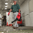 This is an image of a man using a Milwaukee leaf blower in a warehouse setting, featured by Kennedys Welding Supplies in Derwent Park, Tasmania, offering tool shop and power tool repairs.