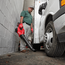 This is an image of a man using a red Milwaukee blower to clean debris beside a white truck, showcasing tools at Kennedys Welding Supplies in Derwent Park, TAS
