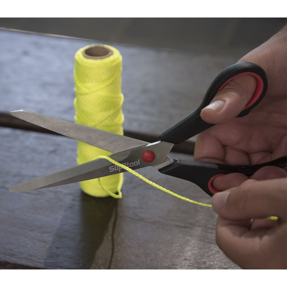 This is an image of Supatool scissors cutting yellow string with spool in background, Kennedys Welding Supplies in Derwent Park TAS